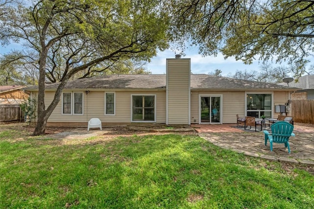 back of property featuring a patio area, fence, a chimney, and a lawn