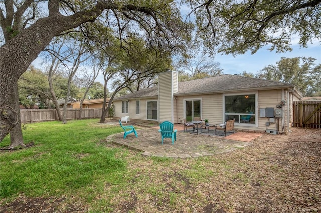 back of house featuring a fenced backyard, a shingled roof, a yard, a chimney, and a patio area