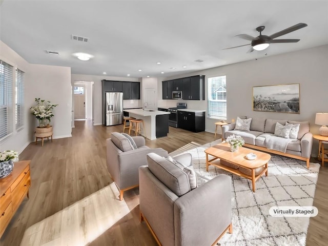 living room with hardwood / wood-style floors, sink, and ceiling fan