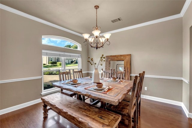 dining space with dark hardwood / wood-style flooring, ornamental molding, and an inviting chandelier