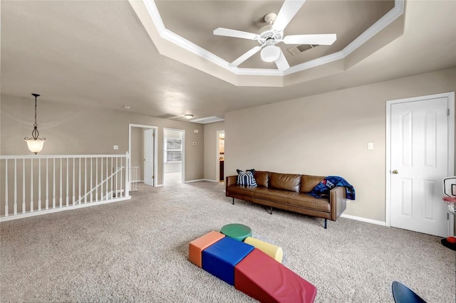 carpeted living room with crown molding, a raised ceiling, and ceiling fan