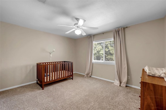 bedroom with a crib, carpet floors, and ceiling fan