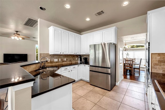 kitchen featuring white cabinets, sink, stainless steel fridge, and kitchen peninsula