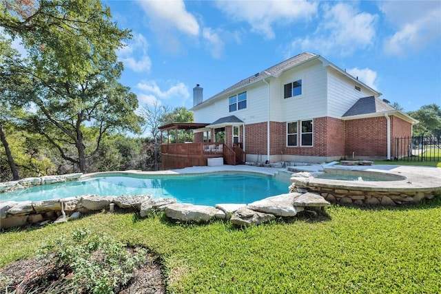 view of pool with a wooden deck, an in ground hot tub, and a lawn