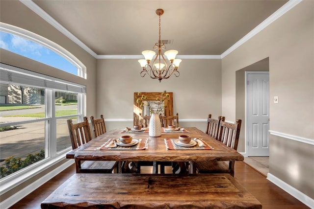 dining area with a notable chandelier, ornamental molding, and dark hardwood / wood-style floors