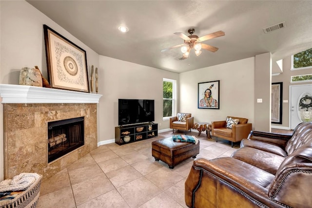 tiled living room with ceiling fan and a fireplace