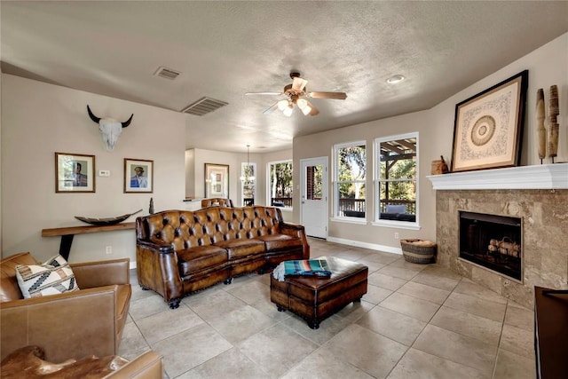 tiled living room with a tiled fireplace, a textured ceiling, and ceiling fan