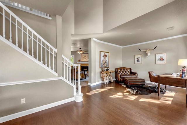 foyer entrance with hardwood / wood-style flooring, ornamental molding, a towering ceiling, and ceiling fan