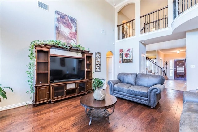 living room featuring a towering ceiling and dark hardwood / wood-style flooring