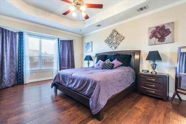 bedroom with ornamental molding, dark hardwood / wood-style floors, and a tray ceiling