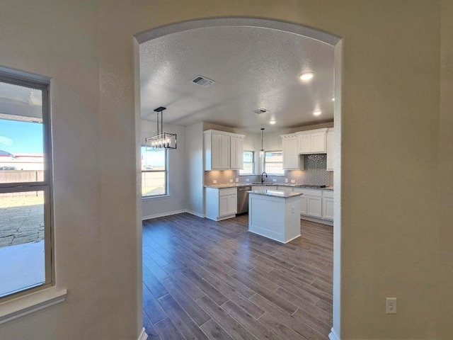 kitchen featuring stainless steel appliances, wood-type flooring, white cabinets, a kitchen island, and decorative backsplash