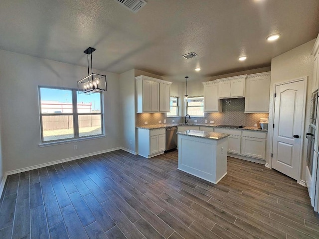 kitchen featuring white cabinetry, a center island, stainless steel dishwasher, and decorative light fixtures