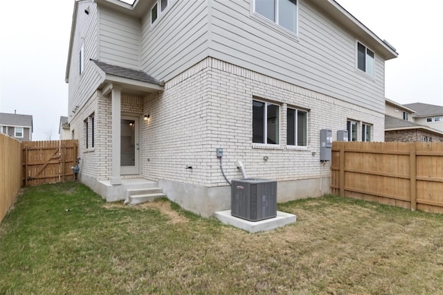 back of property with central AC unit and a lawn