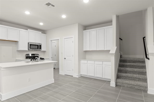 kitchen with stainless steel appliances, sink, light tile patterned floors, and white cabinets