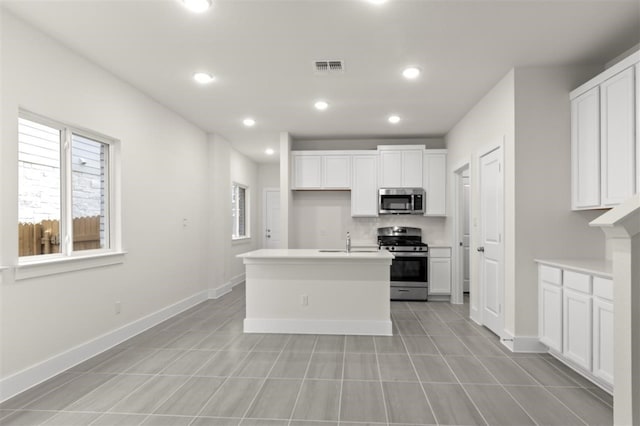 kitchen featuring a kitchen island with sink, sink, white cabinets, and appliances with stainless steel finishes