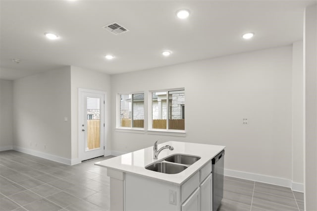 kitchen with sink, light tile patterned floors, dishwasher, a kitchen island with sink, and white cabinetry