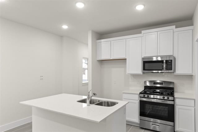 kitchen featuring white cabinetry, sink, backsplash, a kitchen island with sink, and stainless steel appliances