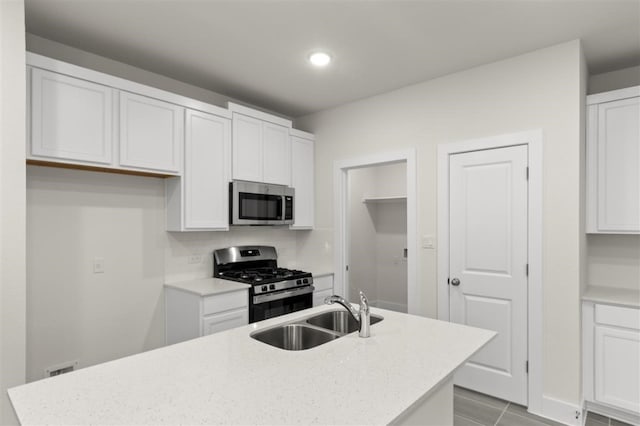 kitchen with white cabinetry, sink, light stone counters, and appliances with stainless steel finishes