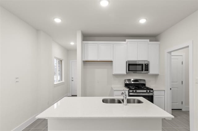 kitchen featuring appliances with stainless steel finishes, white cabinetry, sink, a kitchen island with sink, and light tile patterned floors