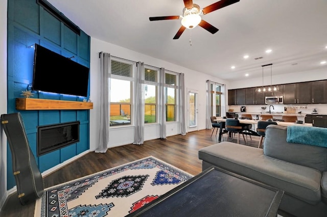 living room with ceiling fan, sink, dark wood-type flooring, and a fireplace