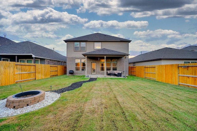 back of property featuring a yard, a patio area, and an outdoor fire pit