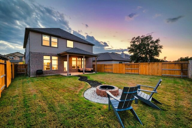 1632 Stone House, New Braunfels, TX 78132 - back of property at dusk with a fire pit, a fenced backyard, brick siding, and a patio area