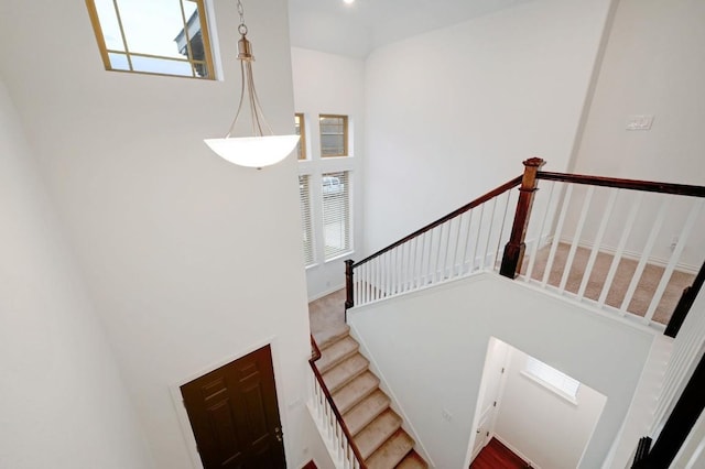 stairs featuring a towering ceiling and a healthy amount of sunlight