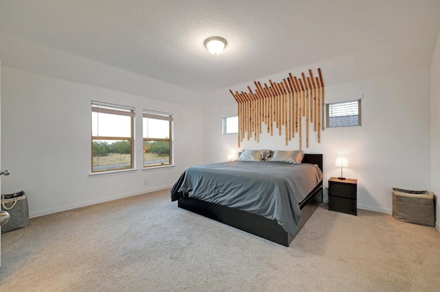 bedroom with light colored carpet and a textured ceiling