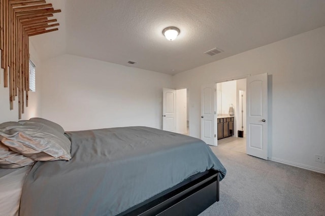 carpeted bedroom featuring connected bathroom and a textured ceiling