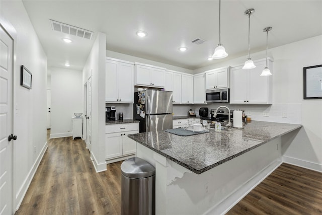 kitchen featuring dark wood-type flooring, white cabinetry, hanging light fixtures, stainless steel appliances, and kitchen peninsula