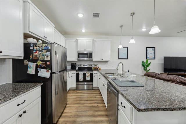kitchen with stainless steel appliances, white cabinetry, a center island, and decorative light fixtures