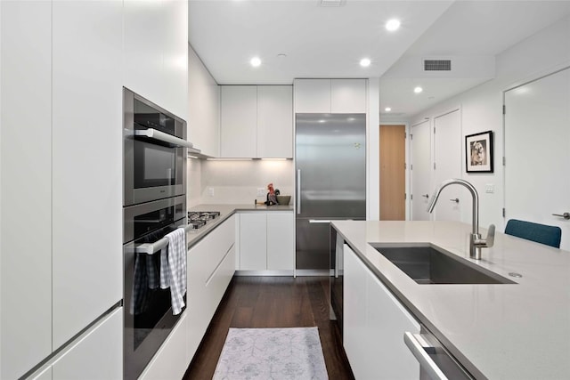 501 W Ave Unit 1403, Austin, TX 78701 - kitchen with stainless steel appliances, modern cabinets, white cabinetry, dark wood-style floors, and light countertops