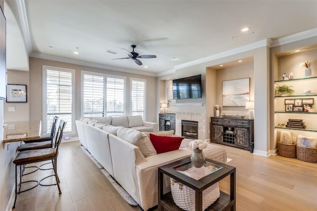 living room featuring built in features, ornamental molding, light hardwood / wood-style floors, and ceiling fan