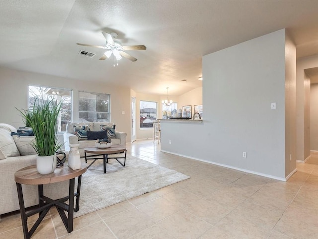 living room with ceiling fan with notable chandelier, vaulted ceiling, and light tile patterned flooring