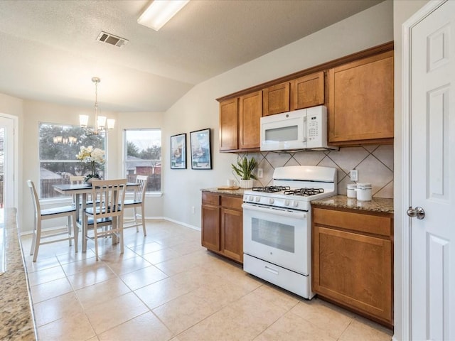 kitchen featuring lofted ceiling, an inviting chandelier, hanging light fixtures, white appliances, and decorative backsplash