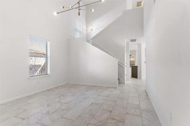 unfurnished living room with a notable chandelier and a high ceiling