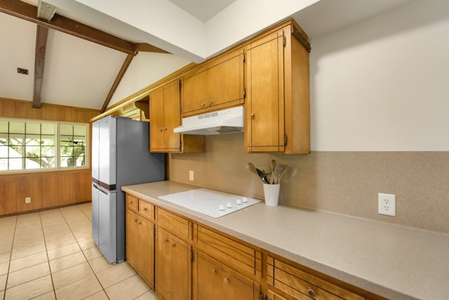 kitchen featuring stainless steel refrigerator, wood walls, vaulted ceiling with beams, light tile patterned floors, and white electric stovetop