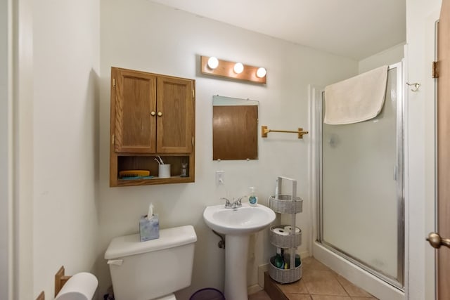 bathroom featuring sink, a shower with shower door, tile patterned floors, and toilet