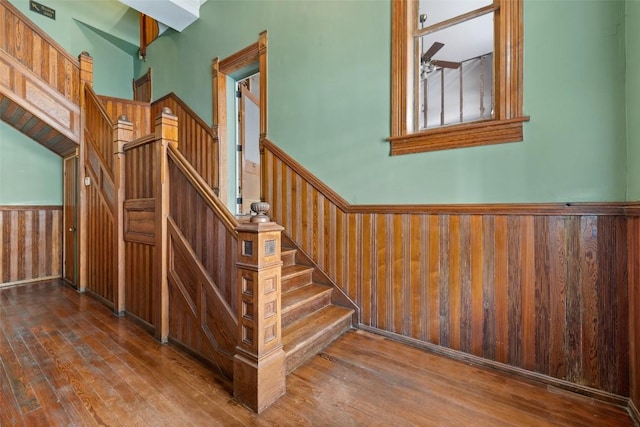 stairway featuring ceiling fan, hardwood / wood-style floors, and wood walls