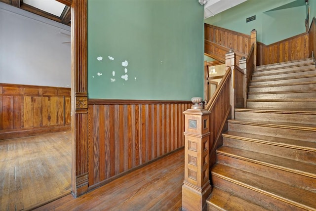 staircase with hardwood / wood-style flooring and wood walls