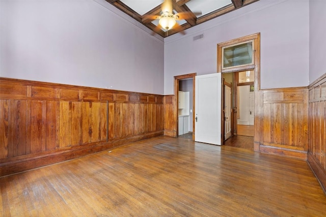 unfurnished room with ceiling fan, a towering ceiling, coffered ceiling, dark hardwood / wood-style flooring, and beamed ceiling