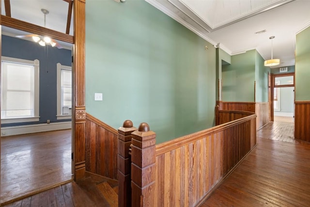 hall featuring crown molding, dark wood-type flooring, and wooden walls