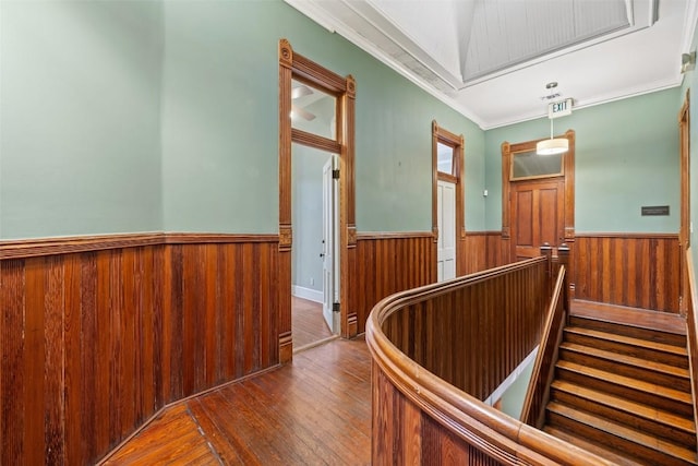 hallway with hardwood / wood-style flooring, wooden walls, and crown molding