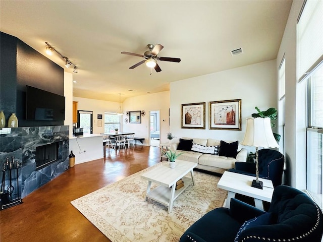 living room featuring rail lighting, ceiling fan, and a high end fireplace