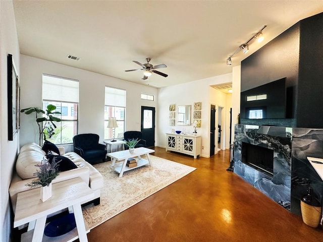 living room with track lighting, ceiling fan, and concrete floors