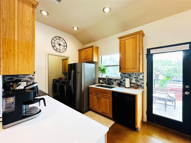 kitchen with washing machine and dryer, vaulted ceiling, sink, dishwasher, and stainless steel fridge