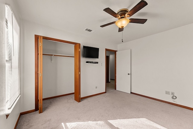 unfurnished bedroom featuring multiple windows, light carpet, a closet, and ceiling fan