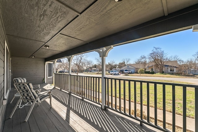 wooden terrace with covered porch and a lawn