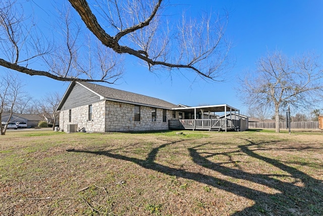 exterior space featuring central AC unit, a deck, and a lawn