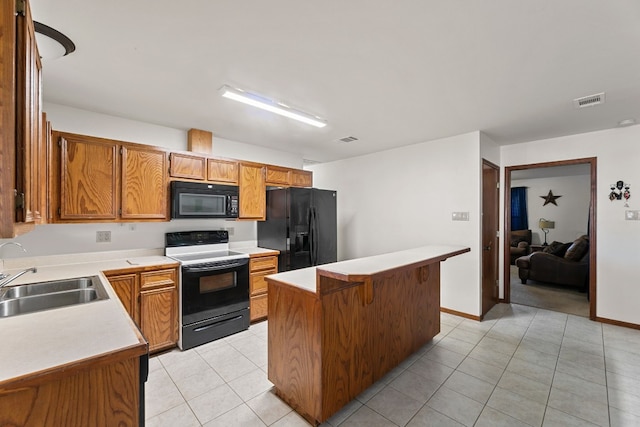 kitchen featuring a kitchen bar, sink, light tile patterned floors, a kitchen island, and black appliances